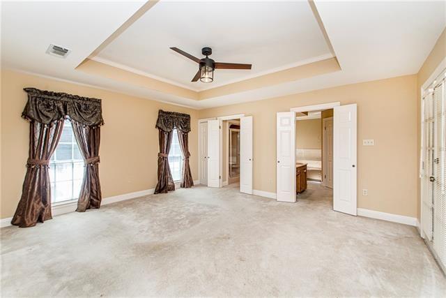 unfurnished bedroom with a raised ceiling, light carpet, and baseboards