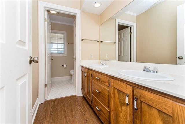 bathroom featuring toilet, ornamental molding, double vanity, baseboards, and wood finished floors