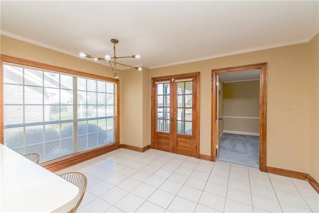 unfurnished dining area featuring a chandelier, ornamental molding, french doors, and baseboards