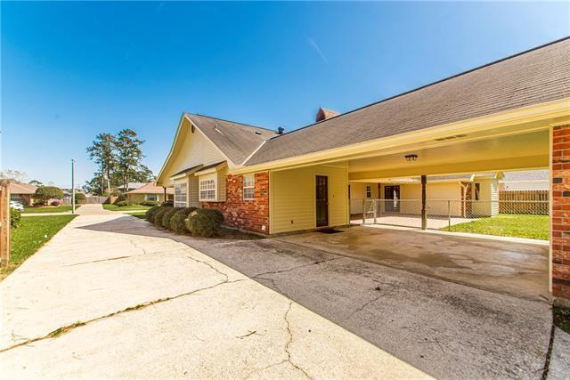 view of side of property with fence, brick siding, a carport, and asphalt driveway