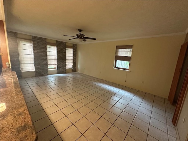 empty room featuring light tile patterned flooring, ceiling fan, and ornamental molding