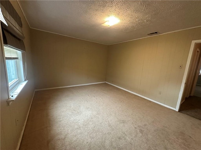 unfurnished room featuring a textured ceiling, visible vents, carpet floors, and baseboards