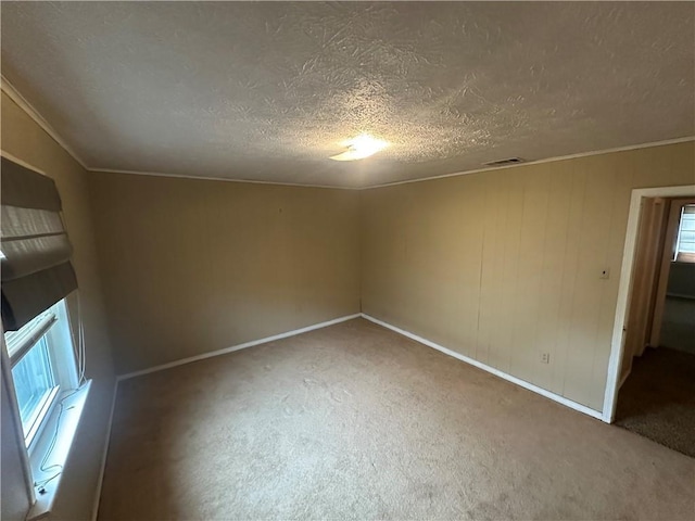 spare room with a textured ceiling, visible vents, carpet flooring, and baseboards