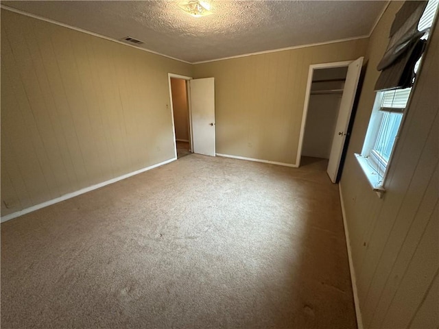 unfurnished bedroom with a closet, carpet flooring, visible vents, a textured ceiling, and crown molding