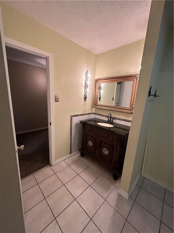 bathroom featuring baseboards, a textured ceiling, tile patterned flooring, and vanity