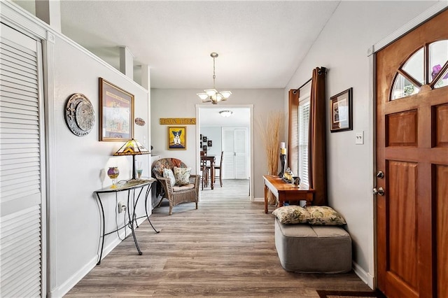 entrance foyer featuring baseboards, wood finished floors, and a notable chandelier