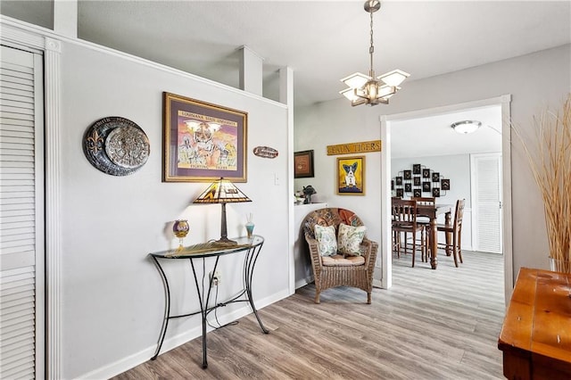living area with baseboards, wood finished floors, and an inviting chandelier
