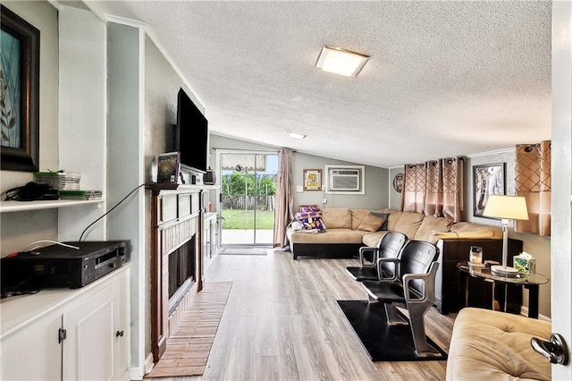 living area with vaulted ceiling, a fireplace, an AC wall unit, light wood-type flooring, and a textured ceiling