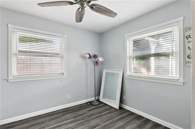 spare room featuring dark wood-type flooring, ceiling fan, and baseboards