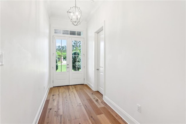 doorway to outside with an inviting chandelier, light wood-type flooring, and baseboards