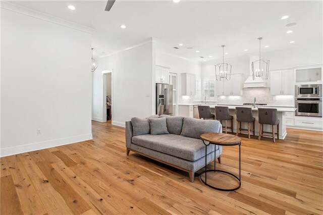 living room with recessed lighting, an inviting chandelier, baseboards, and light wood-style floors