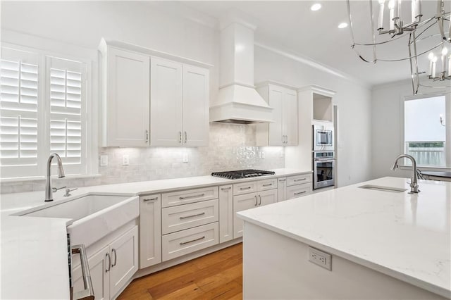 kitchen with white cabinetry, stainless steel appliances, crown molding, and a sink
