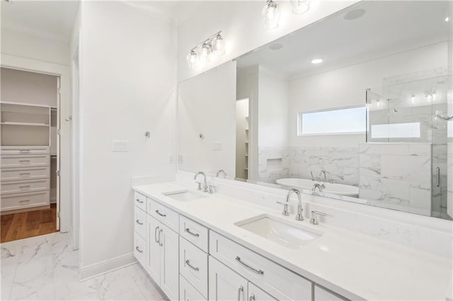 full bath featuring a tub to relax in, a marble finish shower, a sink, and marble finish floor