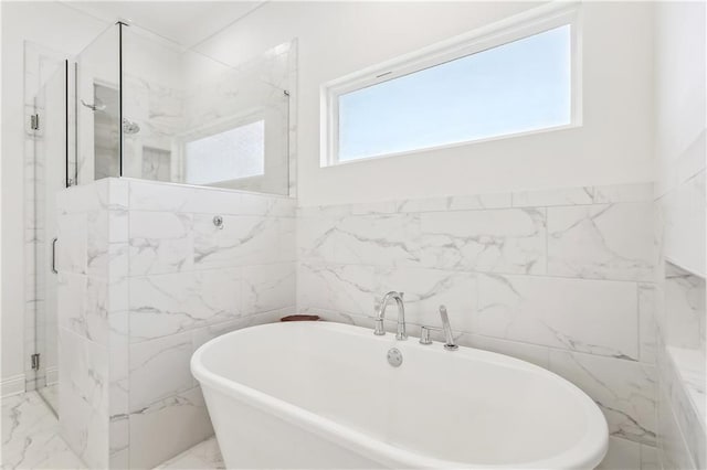 bathroom with tile walls, a marble finish shower, a soaking tub, and marble finish floor