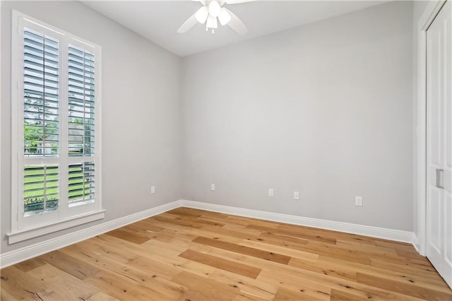 spare room with a ceiling fan, light wood-style floors, and baseboards