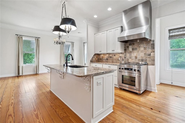386 Marina Blvd, Mandeville, LA 70471 - kitchen with a sink, wall chimney range hood, stainless steel stove, light wood-style flooring, and light stone counters