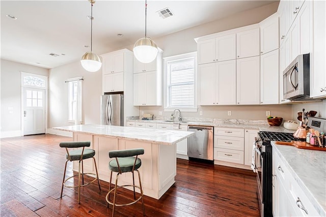 2119 Bienville St, New Orleans, LA 70112 - kitchen with a sink, appliances with stainless steel finishes, a breakfast bar, visible vents, and dark wood-style floors