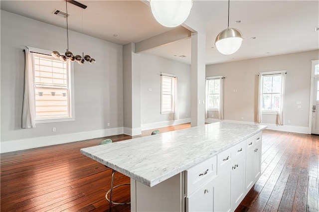 2119 Bienville St, New Orleans, LA 70112 - kitchen featuring dark wood finished floors, light stone countertops, white cabinetry, visible vents, and open floor plan