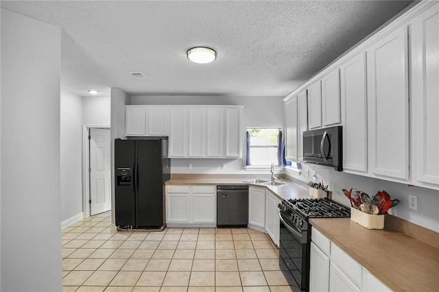2254 9th St, Mandeville, LA 70471 - kitchen with black appliances, a sink, white cabinetry, light tile patterned flooring, and a textured ceiling