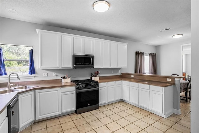2254 9th St, Mandeville, LA 70471 - kitchen featuring stainless steel appliances, a sink, light tile patterned floors, white cabinetry, and a peninsula
