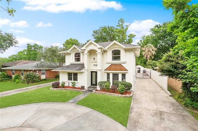 view of front of home featuring a gate, stucco siding, a front yard, and concrete driveway