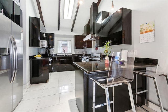 kitchen featuring light tile patterned floors, lofted ceiling with beams, a peninsula, wall chimney range hood, and appliances with stainless steel finishes
