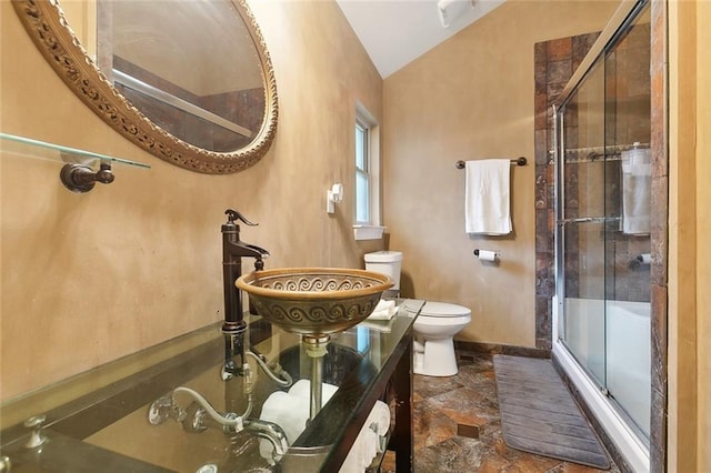 bathroom with stone finish flooring, toilet, vaulted ceiling, baseboards, and a shower with door