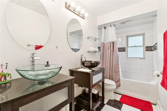 bathroom with two vanities, shower / bath combo with shower curtain, toilet, and a sink