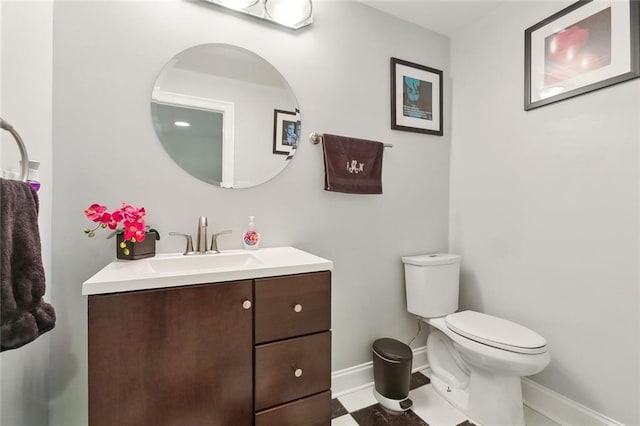 half bathroom with baseboards, toilet, and vanity