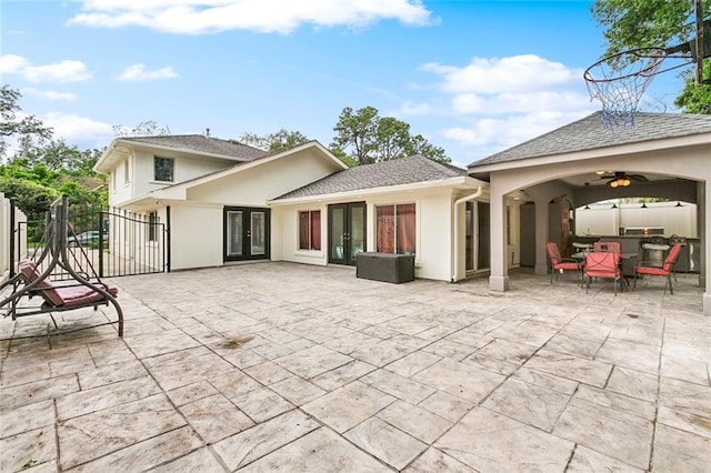 rear view of house with stucco siding, fence, a patio area, french doors, and a ceiling fan