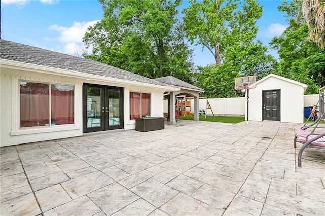 view of patio featuring fence, a storage shed, french doors, and an outbuilding