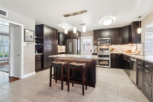 535 Amethyst St, New Orleans, LA 70124 - kitchen with visible vents, a center island, tasteful backsplash, light stone counters, and stainless steel appliances