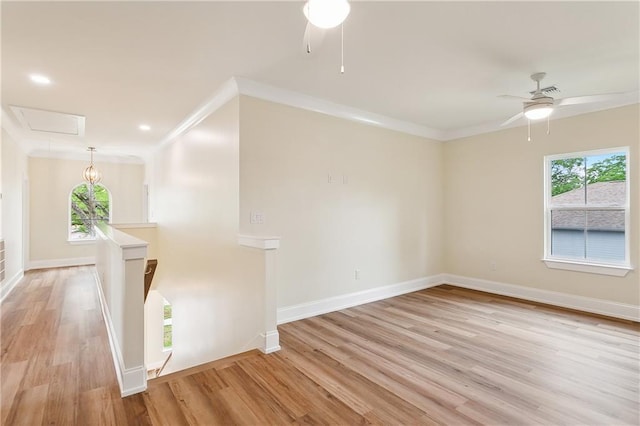 unfurnished room featuring ceiling fan, light wood finished floors, a wealth of natural light, and attic access