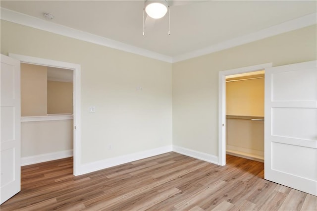 unfurnished bedroom featuring baseboards, a closet, light wood finished floors, and a spacious closet