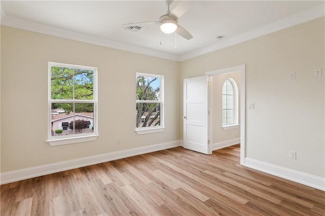 empty room featuring crown molding, ceiling fan, light wood-style floors, baseboards, and visible vents