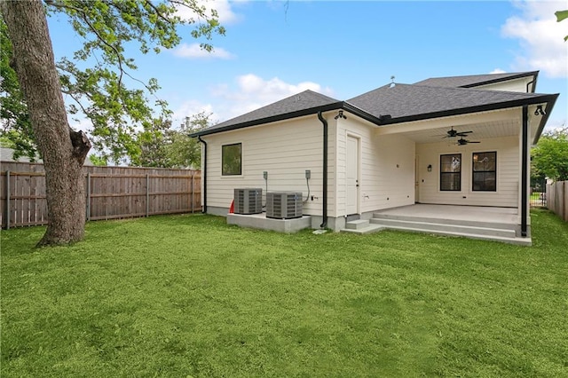 back of property with a patio, a fenced backyard, a ceiling fan, a shingled roof, and a yard