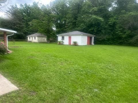 view of yard with a detached garage, a storage unit, and an outdoor structure