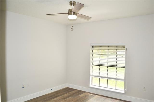 empty room with wood finished floors, a ceiling fan, and baseboards
