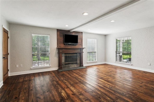 unfurnished living room with a fireplace, a textured wall, plenty of natural light, and wood-type flooring