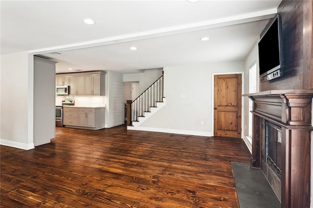 unfurnished living room featuring recessed lighting, stairs, baseboards, a fireplace with flush hearth, and dark wood-style floors