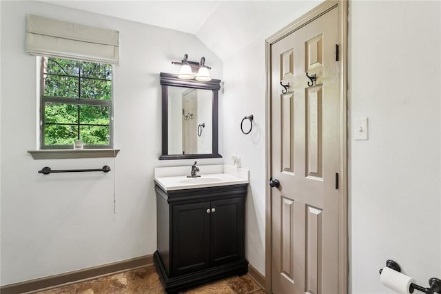 bathroom featuring vanity, vaulted ceiling, and baseboards