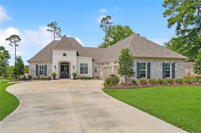 french country home with a shingled roof, a front lawn, driveway, and an attached garage