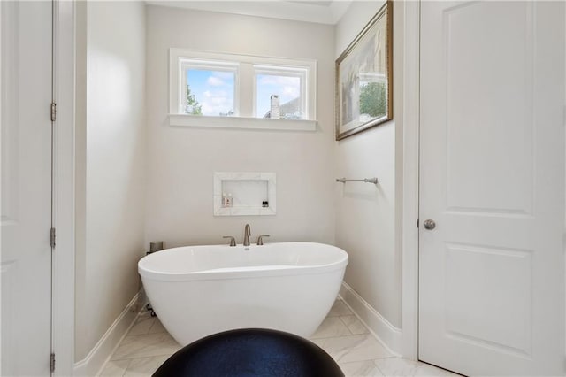 full bath with marble finish floor, a soaking tub, and baseboards
