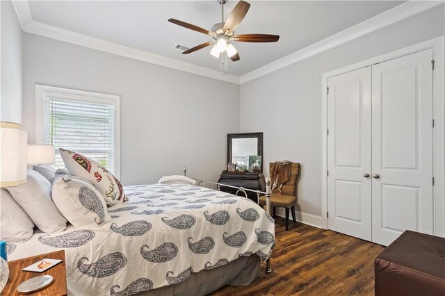 bedroom featuring dark wood-style flooring, a closet, ceiling fan, visible vents, and ornamental molding