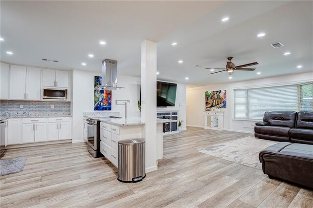 208 Bedford St, La Place, LA 70068 - kitchen featuring island exhaust hood, open floor plan, appliances with stainless steel finishes, a ceiling fan, and light wood-type flooring