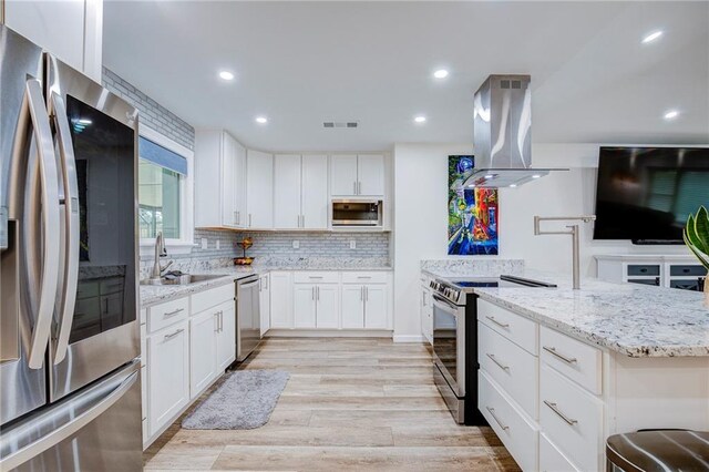 208 Bedford St, La Place, LA 70068 - kitchen featuring appliances with stainless steel finishes, island exhaust hood, a sink, light stone counters, and light wood-style floors