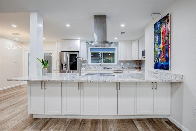 208 Bedford St, La Place, LA 70068 - kitchen with appliances with stainless steel finishes, island range hood, white cabinetry, light stone countertops, and recessed lighting