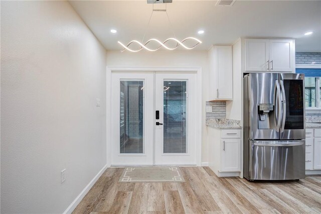 208 Bedford St, La Place, LA 70068 - kitchen with stainless steel fridge with ice dispenser, french doors, light wood-style flooring, white cabinetry, and tasteful backsplash