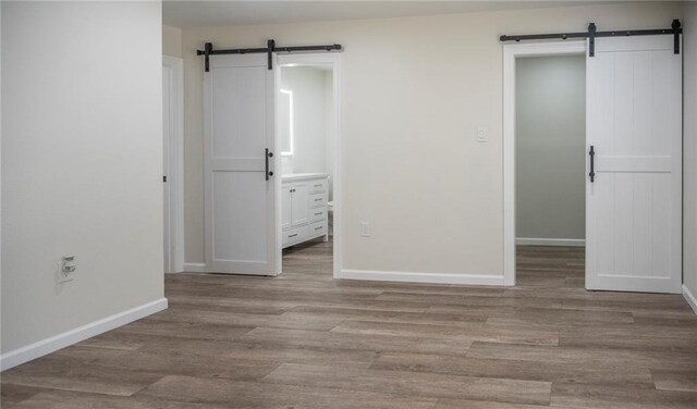 208 Bedford St, La Place, LA 70068 - empty room with a barn door, baseboards, and wood finished floors