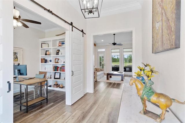 hallway featuring crown molding, wood finished floors, a barn door, and baseboards